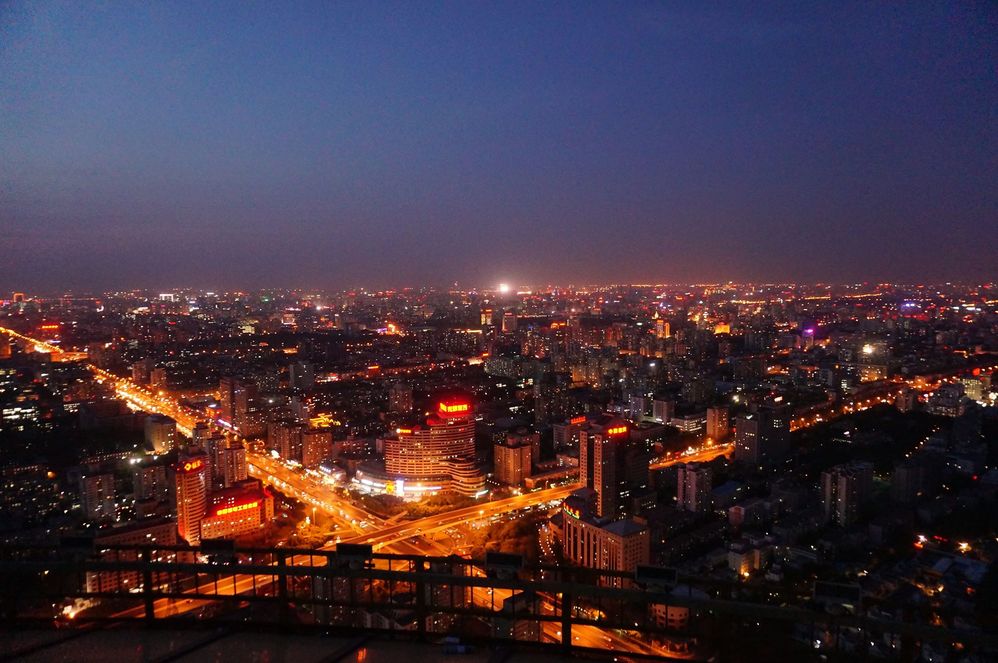 描述：从老中央电视台塔上看北京的日落之后的景象。天空是靛蓝色的，街道上和建筑物上的橘黄色灯光都亮了。 (本地向导 @TsekoV)