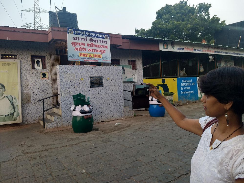 Caption: A photo of Local Guide @Shrut19 taking a picture of the outside of a public toilet in Mumbai, India.
