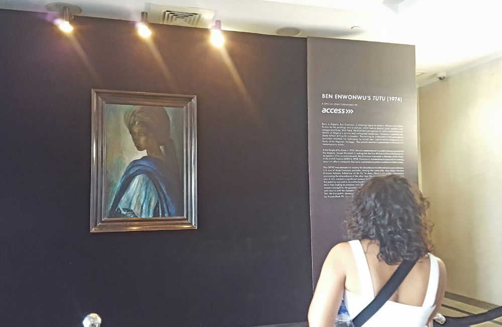Caption: The portrait TuTu displayed on a black background while a guest admires the artwork