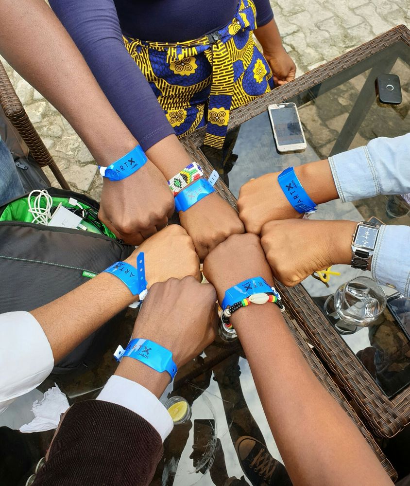 Caption: Local Guides join fists together showing blue Art X wristbands