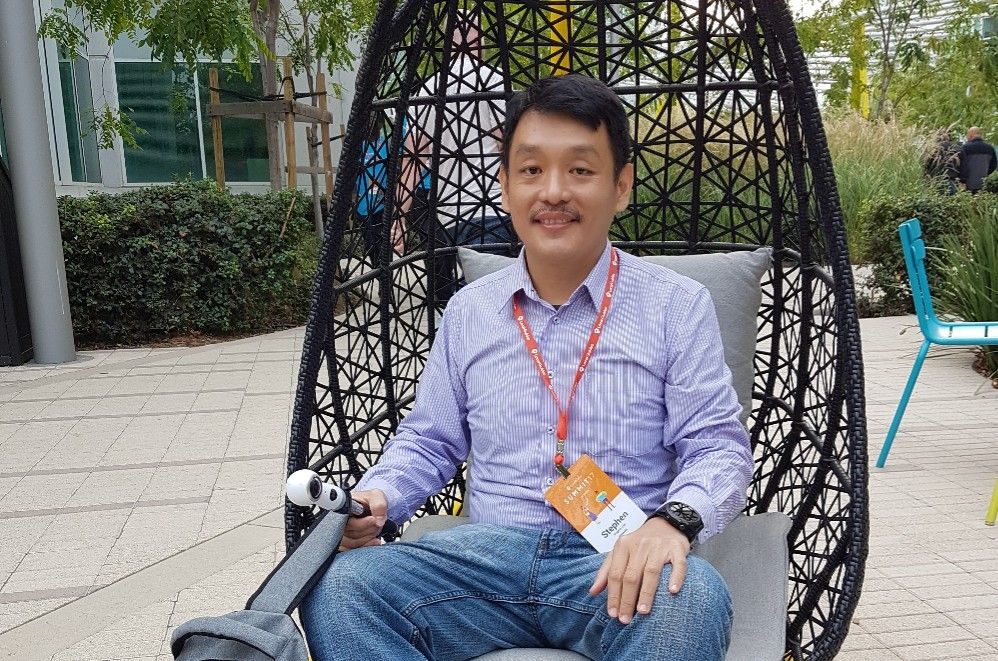 Caption: A photo of Stephen at Local Guides Summit 2017 sitting in a chair outside of Googleplex in Mountain View, CA.