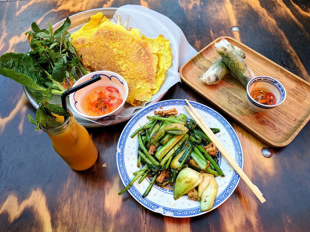 Caption: A variety of colorful gluten-free Vietnamese dishes with chopsticks and a fruit drink at Little V Den Haag, a restaurant in The Hague, Netherlands. (Local Guide Benjamin Richardson)