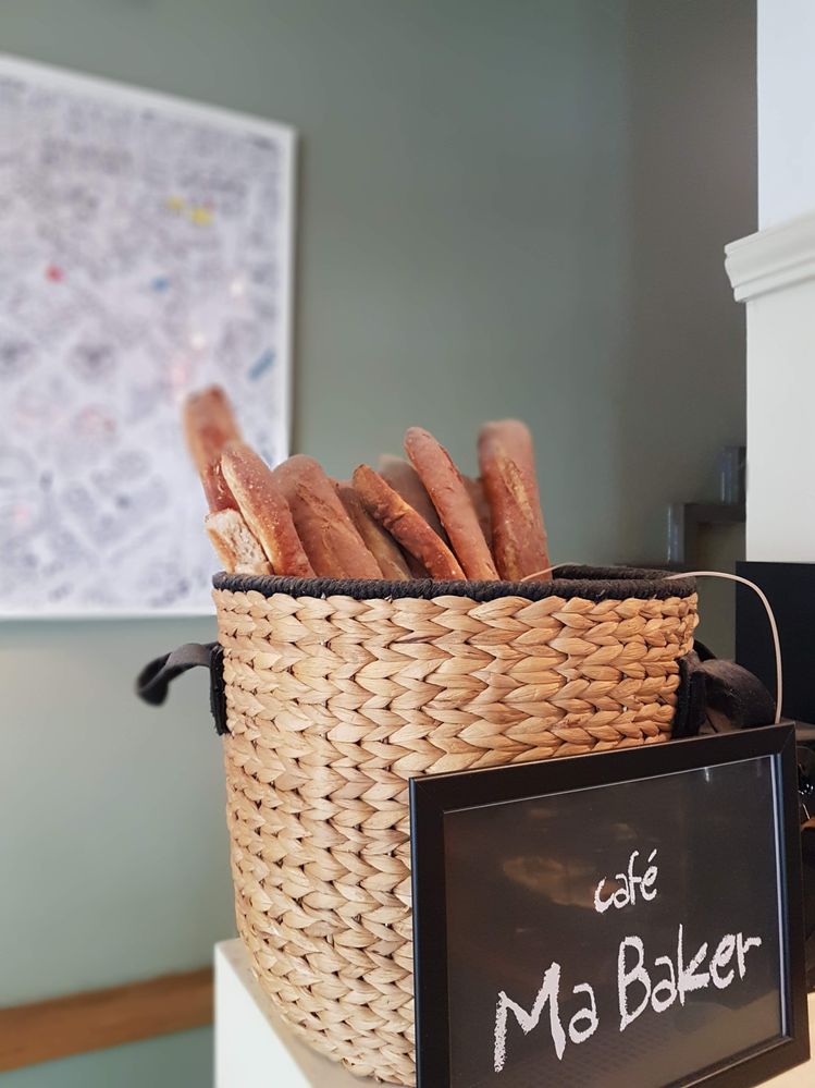 Caption: A photo of a basket of breadsticks, with a sign in front reading “Café Ma Baker.” (Local Guide @InaS)