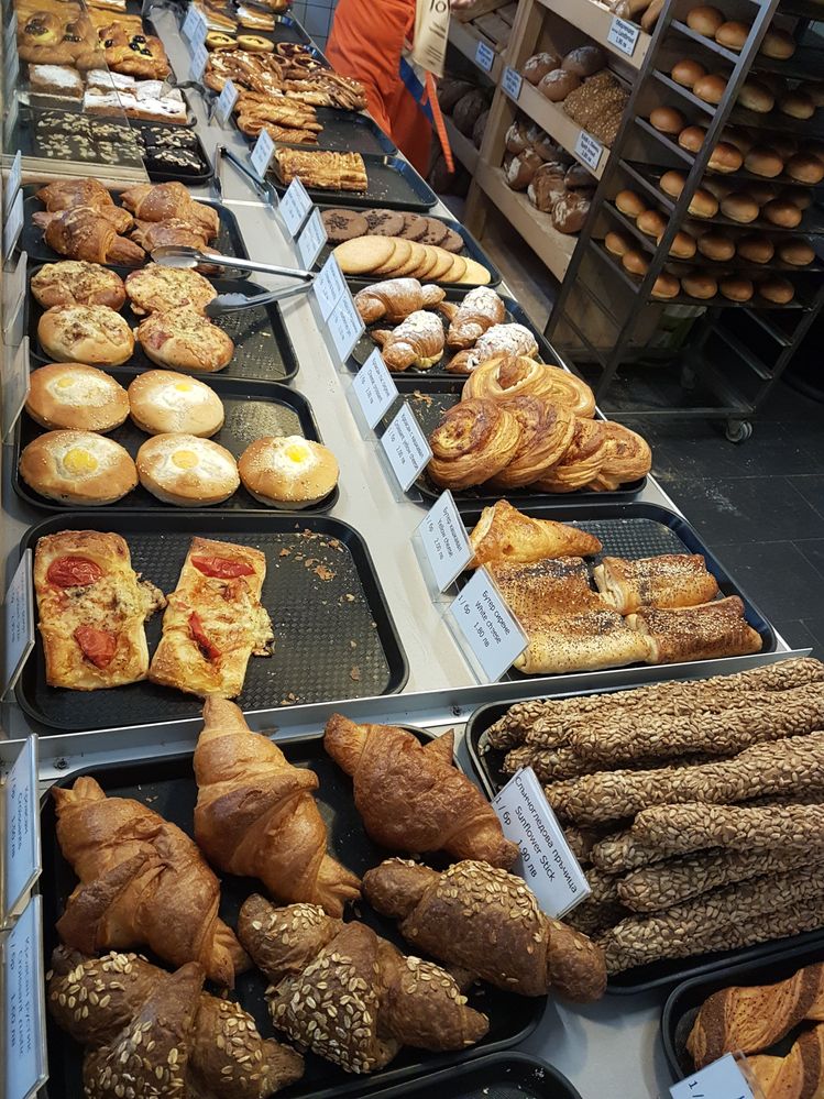 Caption: A photo of baked breads and pastries on trays at JoVan The Dutch Bakery. There are croissants with butter and seeds, breadsticks with sunflower seeds, pastries filled with white and yellow cheese, savory muffins, cookies, brownies, and more.  (Local Guide @InaS)