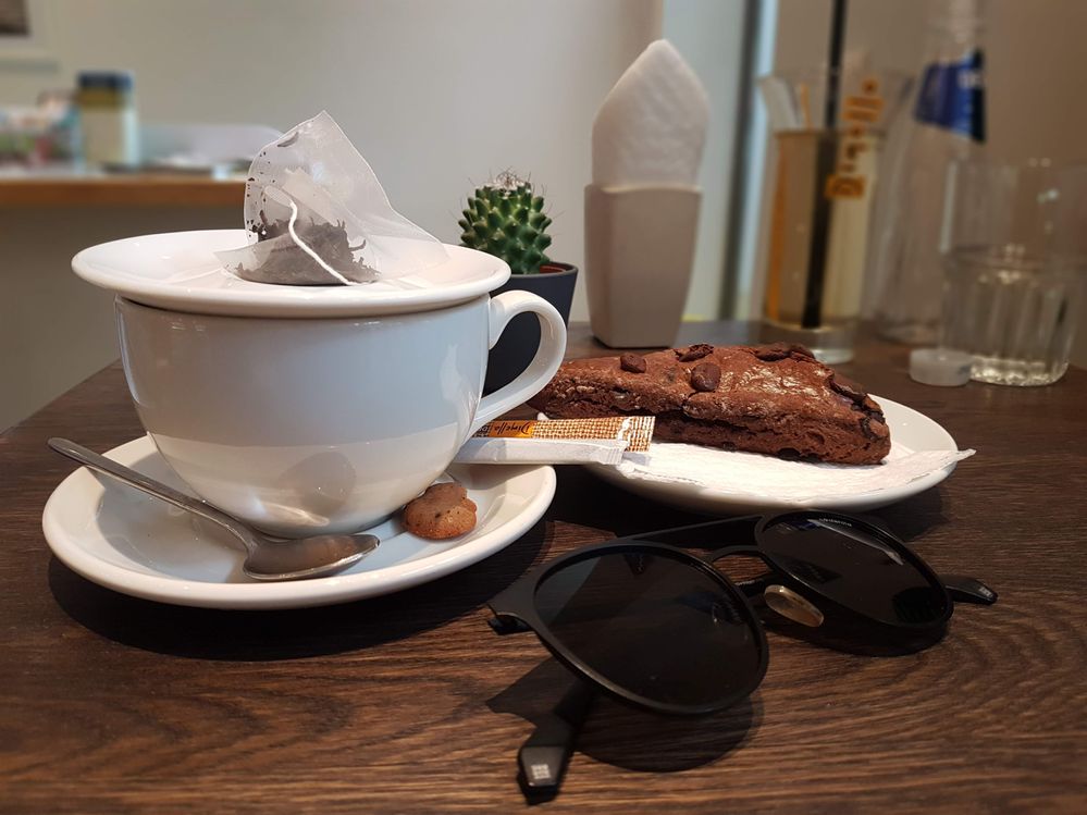 Caption: A photo of a cup of tea, a chocolate brownie and sunglasses on a table at Cakey Bakey. (Local Guide @VasT)