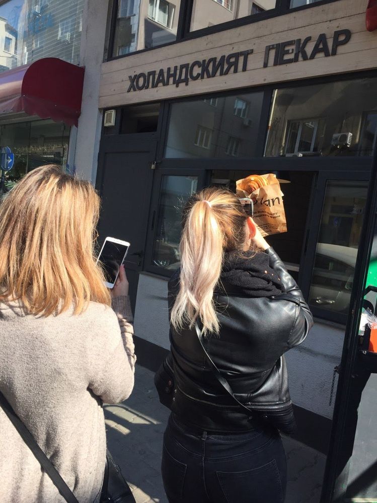 Caption: A photo of the backs of Google Moderators @VasT (left) and @InaS (right), taking photos with their phones in front of the JoVan The Dutch Bakery. (Local Guide @AngieYC )