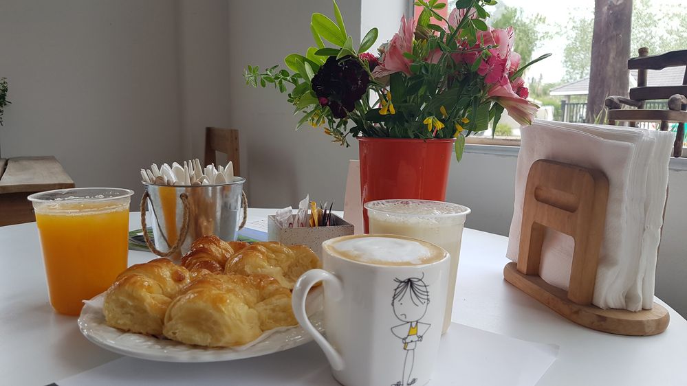 Caption: Pastries, coffee, milkshake and juice on a table with flowers