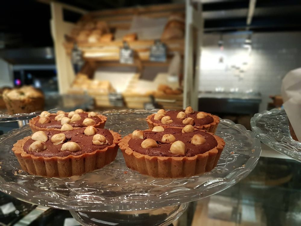 Caption: A tart filled with hazelnut cream and topped with hazelnuts. From Cafe Ma Baker.