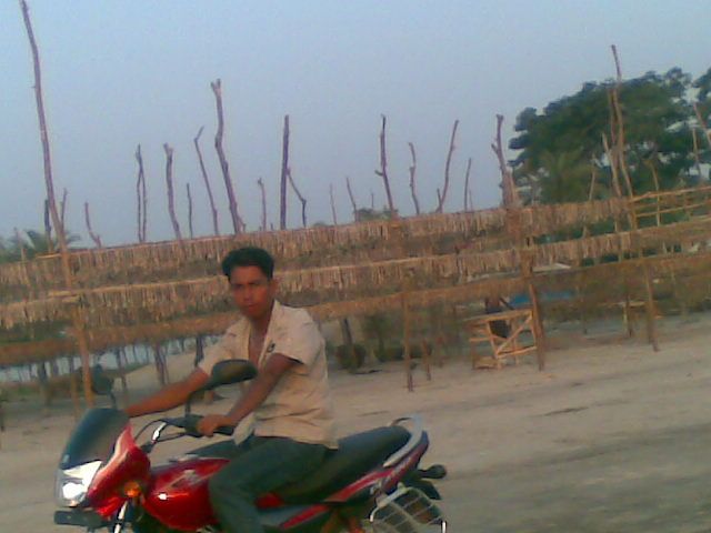 A motorcycle rider in front of dried fish processing yard.