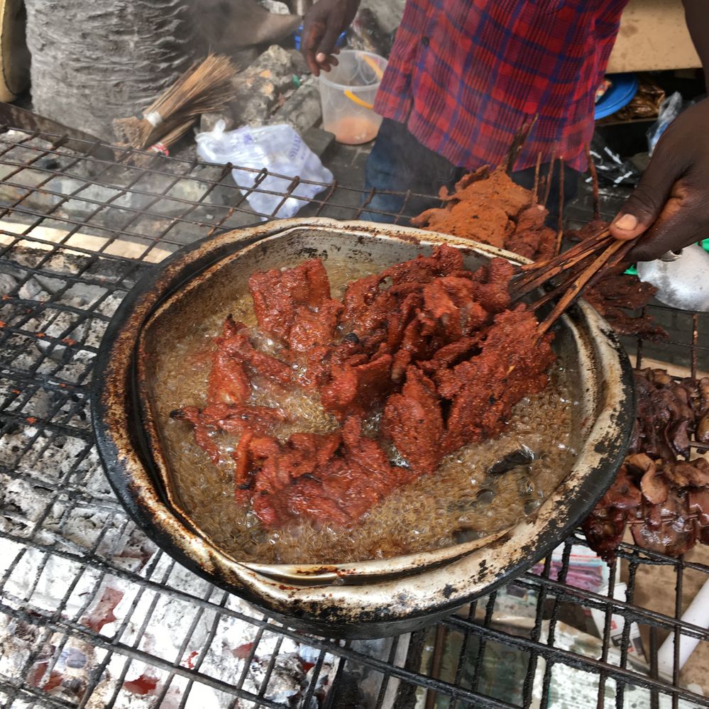 Caption: A photo of a man cooking suya, meat skewers, in boiling oil over a barbecue at Glover Court Suya in Lagos, Nigeria. (Local Guide Mahbub Baset)