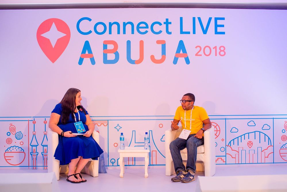 Caption: A photo of Traci Cappiello, the Local Guides Community Program Manager, interviewing Local Guide @EmekaHouse on stage at Connect Live Abuja 2018.