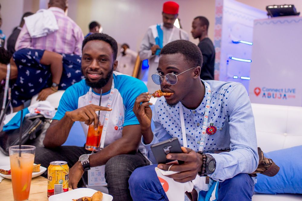 Caption: A photo of two Local Guides posing for the camera as they eat and drink at Connect Live Abuja 2018.