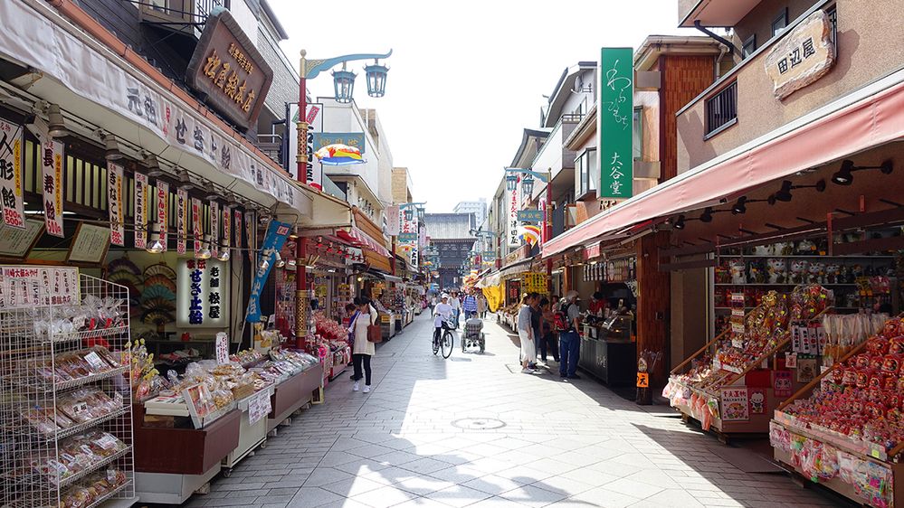 Caption: A photo of a street in Kawasaki, Japan, lined with open-air shops showcasing products for sale. (Local Guide NOR K)