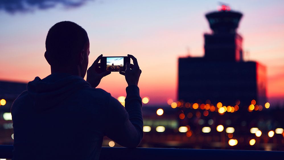 Caption: A photo of a man bracing himself on a railing while taking a photo of a landmark at sunset in Prague. (Getty Images)