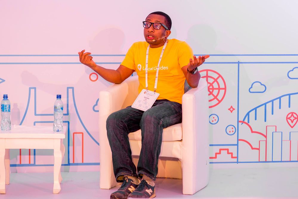 Caption: A photo of Local Guide Emeka Ulor sitting on a white chair sharing his experiences at Connect Live Abuja.