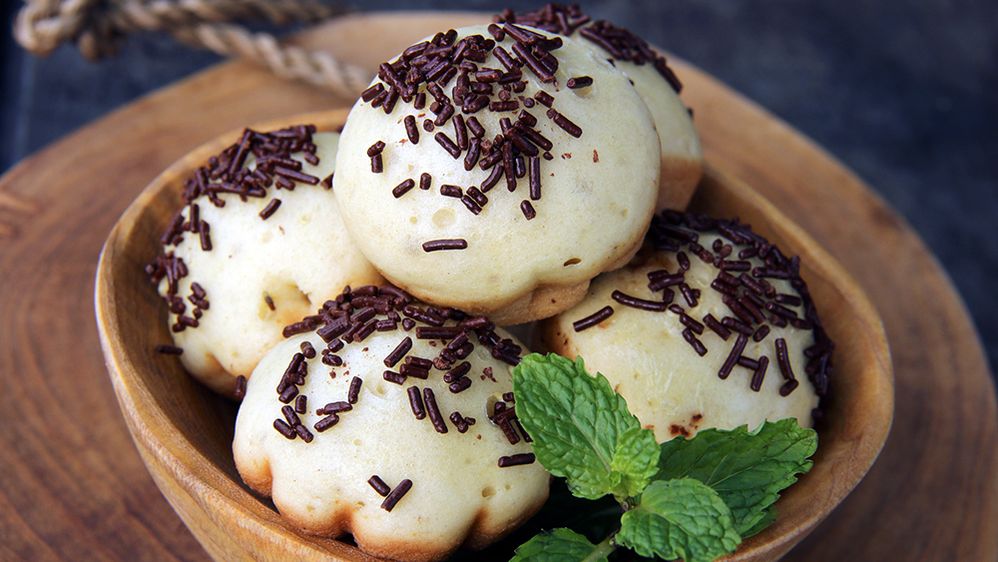 Caption: Tumpukan kue putu dengan taburan kelapa parut diatas daun pisang. (Getty Images)