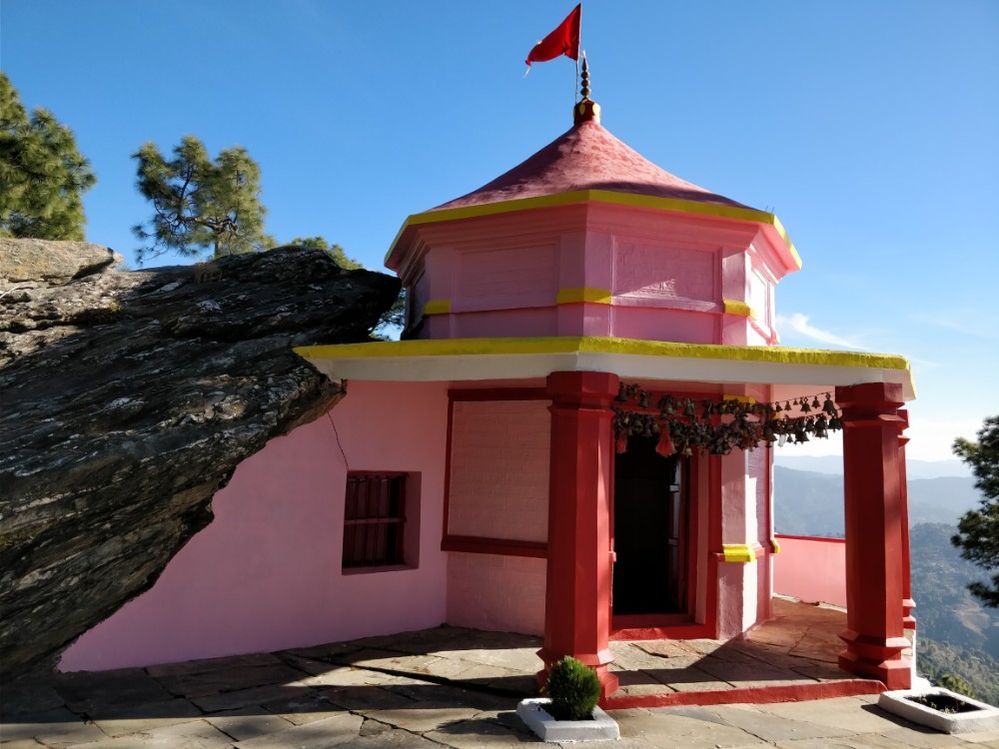 Caption: A photo of the exterior of Kasar Devi Temple, a Hindu temple that’s painted pink, yellow, and red, located in Mat, Uttarakhand, India. (Local Guide Vishal Sharma)