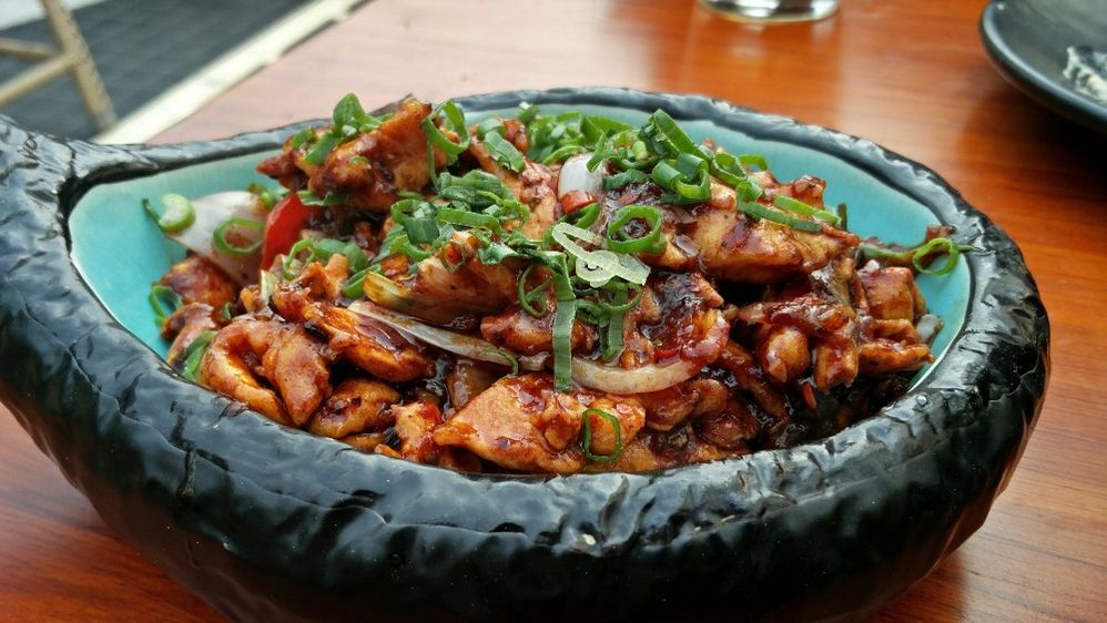 Caption: A closeup photo of a meat dish topped with scallions and served in a black and blue bowl at BOA Village in Delhi, India. (Local Guide sagorika bagchi)