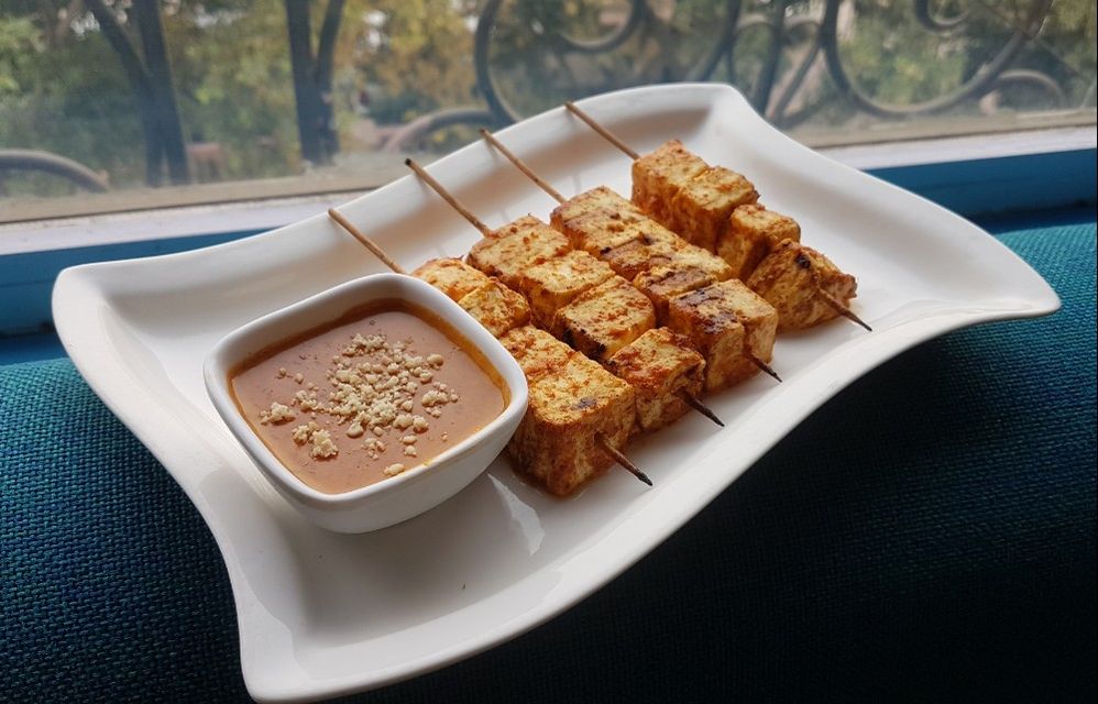 Caption: A photo of a skewer dish next to a small bowl of dipping sauce at Escape Terrace Bar & Kitchen in Gurugram, Haryana, India. (Local Guide Abhishek Rajpu)