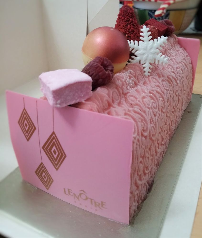 Caption: A photo of a pink bûche de Noël cake from Lenôtre in Paris, France with pink marshmallows, raspberries, white chocolate and a white snowflake. (Local Guide Ako R)