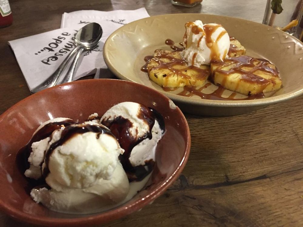 A Photo of the desserts ( Ice cream with hot chocolate sauce , Grilled pineapple - caramel sauce with vanilla ice cream )