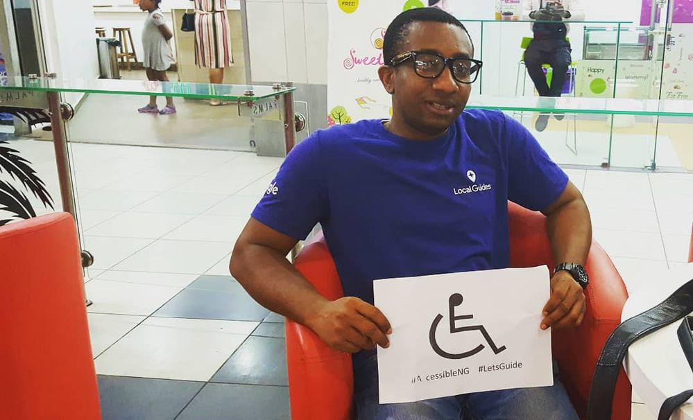 Caption: Local Guide @EmekaHouse holding an accessibility sign at his last meetup in Lagos