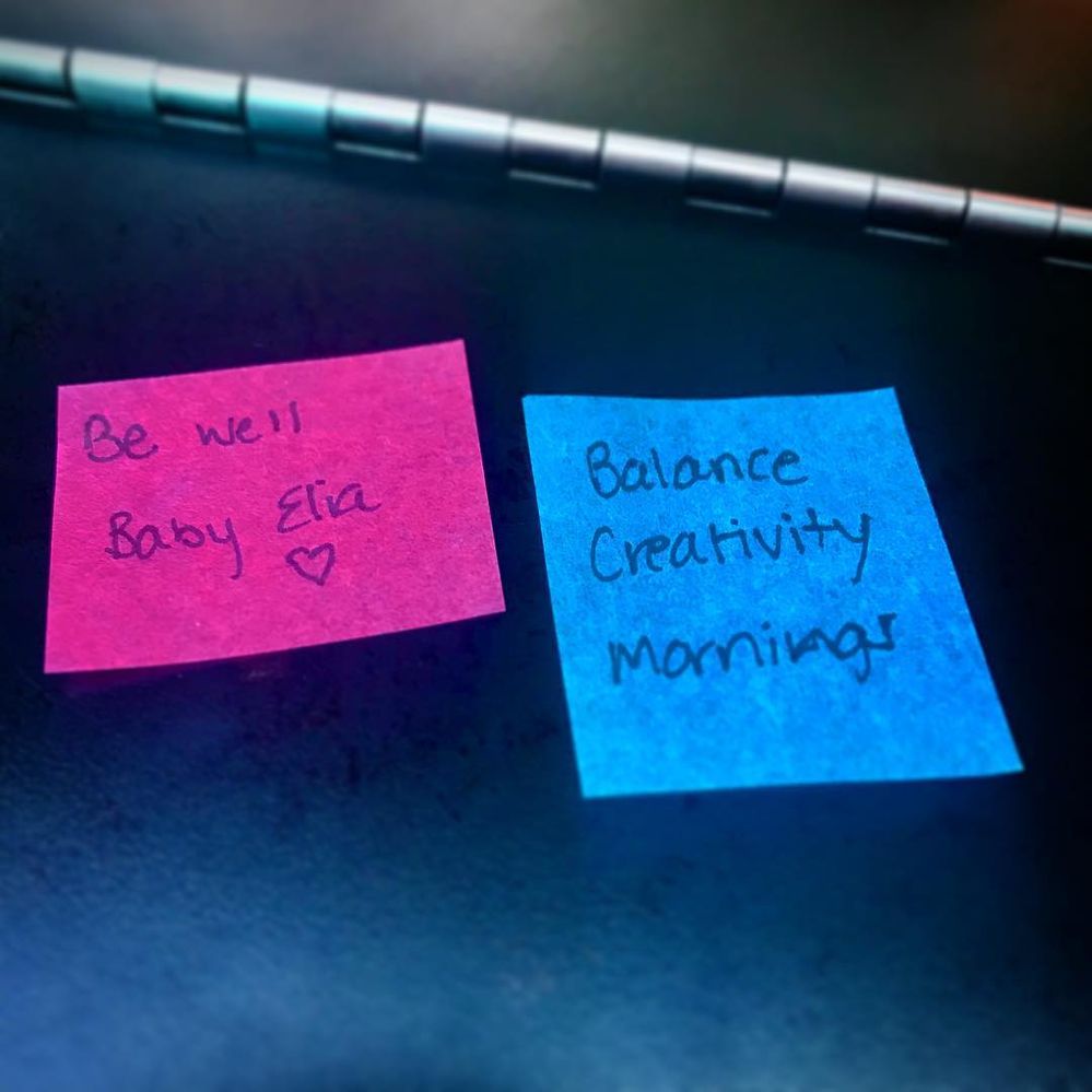 Caption: A handwritten note on a pink confetti square says "Be well Baby Elia," and a handwritten note on a blue confetti square says "Balance, Creativity, Mornings."
