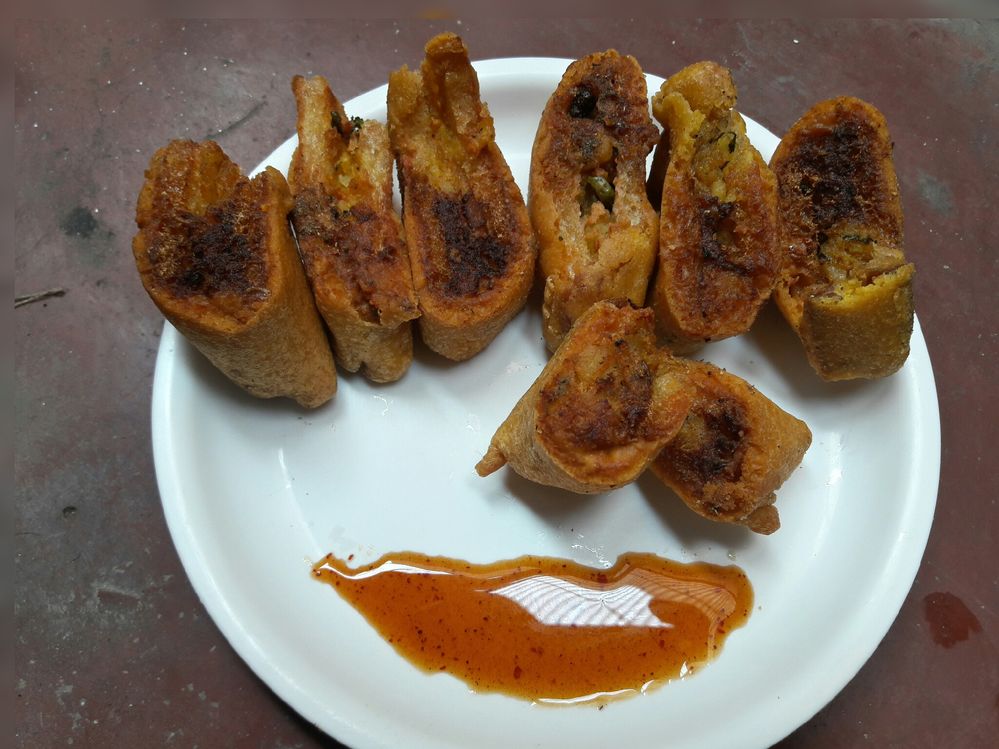 Caption: Bread pakora cutting in some pieces place in a white plate with some sauce.