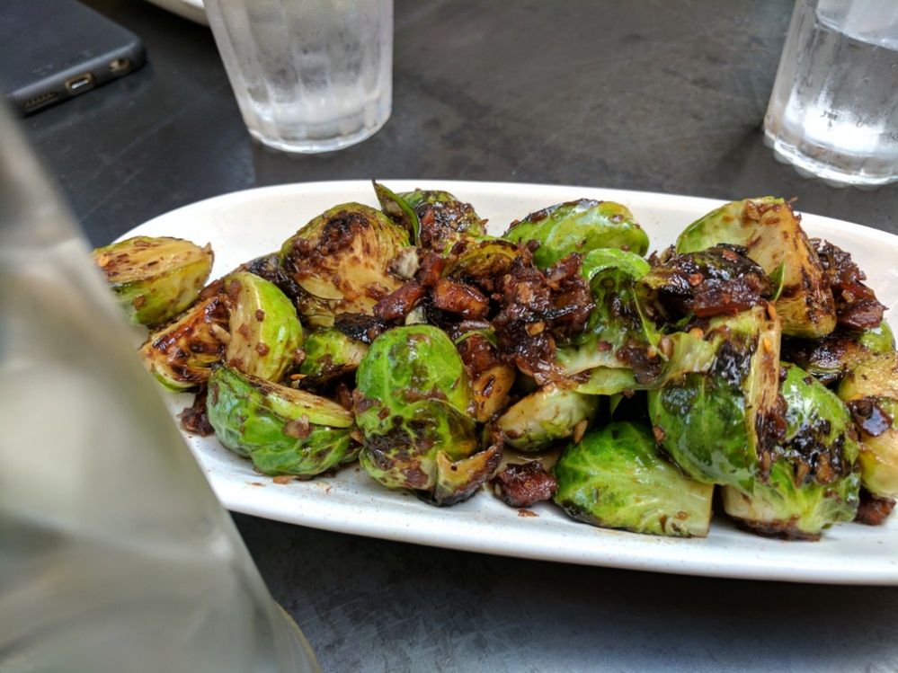 Caption: A photo of a plate of charred brussels sprouts with medjool dates, garlic, chili flakes, and vinaigrette from Freesoulcaffé, a vegan cafe in Tustin, California. (Local Guide Suzanne Nam)