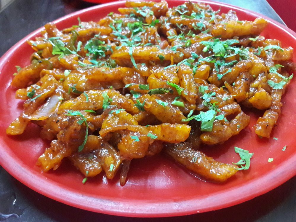 Caption: Chilly potatoes garnish with coriander leaves serve in a red plastic plate ( Photo by Local Guide Ishant Gautam).