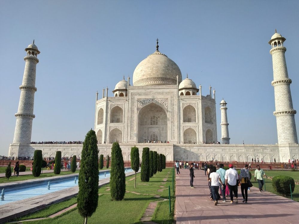 Caption: A photo of the Taj Mahal in Agra, India, a white 17th-century, marble mausoleum and mosque with symmetrical gardens. (Local Guide Satish Kumar)