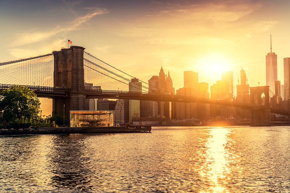 Caption: A photo of Brooklyn Bridge and Jane’s Carousel with Manhattan skyscrapers in the background, taken during sunset in New York, New York. (Getty Images)