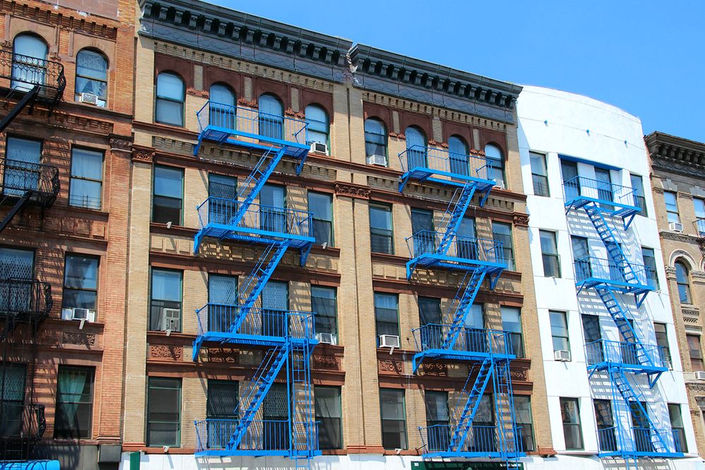 Caption: A photo of buildings with blue fire escapes in New York City, New York. (Getty Images)