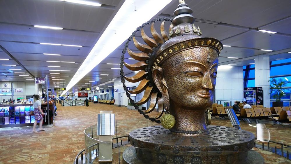 Caption: A photo of the bronze sculpture of the head of Surya in the Indira Gandhi International Airport in Delhi, India. (Local Guide Miros Siemieniuk)
