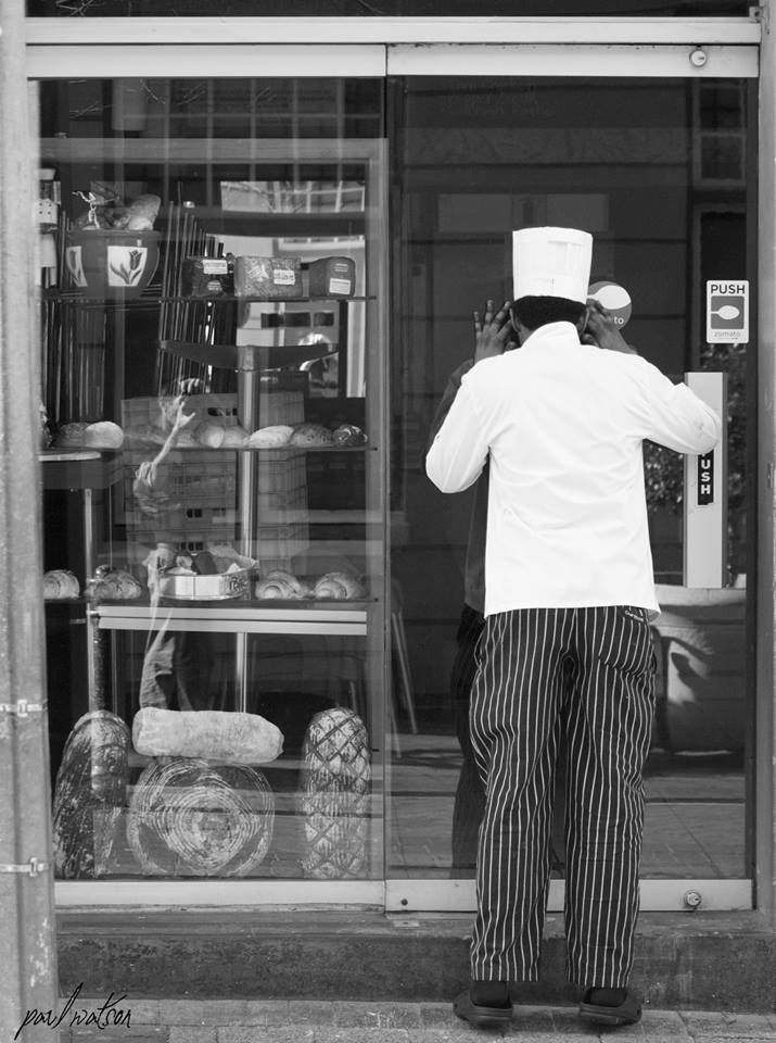 This is a Great Example of some good natured humor. A baker who is locked out his own Bakery. The shot has loads of small detail ( Even me taking the photo in the reflection of the window ) , and only when one picks out  the bakers hat , then the shop items  in the window , does one start to put a story together .  At a glance its not such a bad photo , but a deeper look has you smiling and getting the funny side of things . Taken in Cape Town