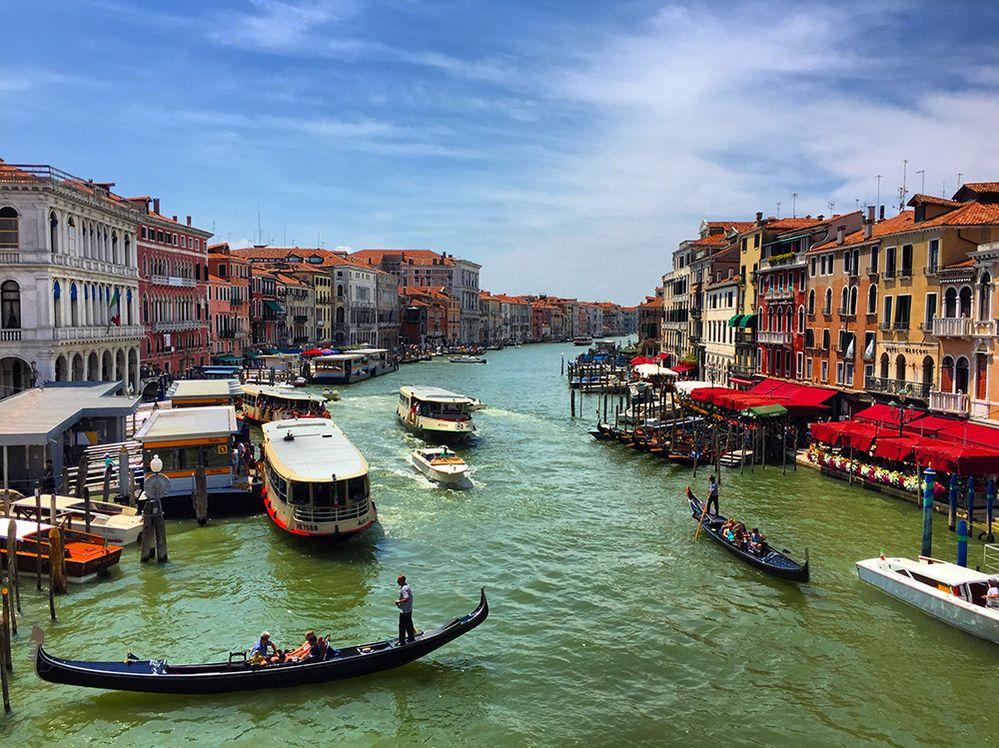 Caption: A photo of the water buses and gondolas on the Grand Canal in Venice, Italy, with colorful buildings lining the canal. (Local Guide Aslau Raluca)