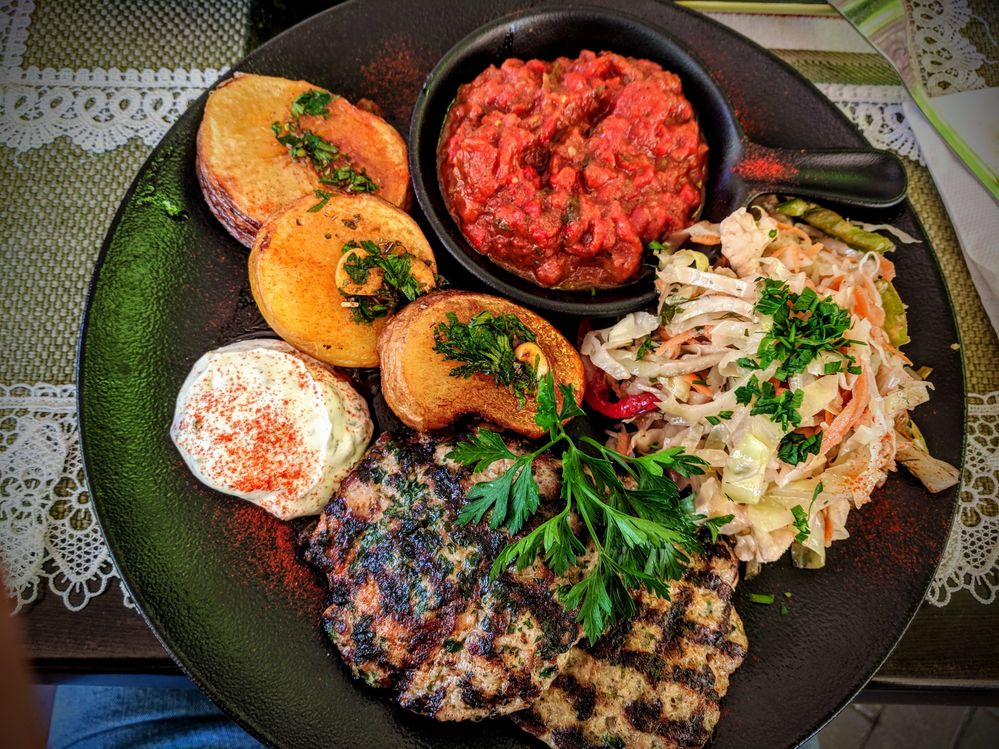 Caption: A photo of two grilled meatballs, roasted potatoes, cabbage salad, a traditional Bulgarian dip liutenitsa and some mayonnaise (Local Guide Dawid Swierczek)