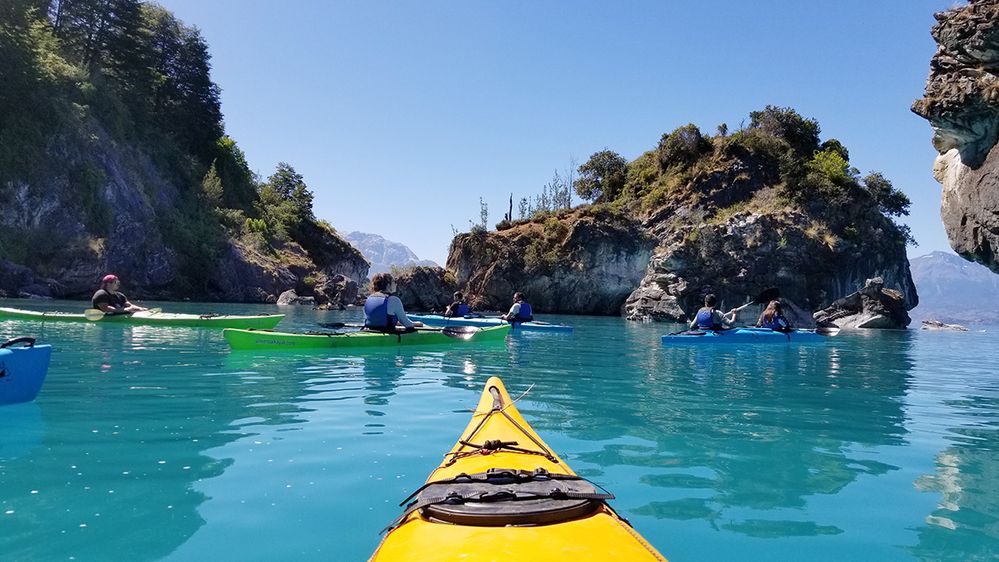 Caption: A photo of the front of a kayak and other kayakers in the water by the Marble Caves in Chile. (Local Guide VykThor)