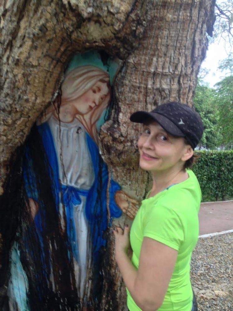 Beatriz recostada sobre un árbol con una pintura de una Advocación Mariana en el Ecoparque de Comfanorte, Los Patios, Colombia.