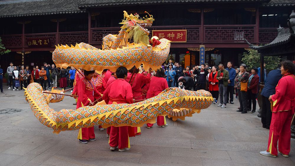 Caption: A photo of Chinese New Year dragon dance performers at a temple in Shanghai, China surrounded by a crowd of people. (Local Guide Chandana Gunatilake)