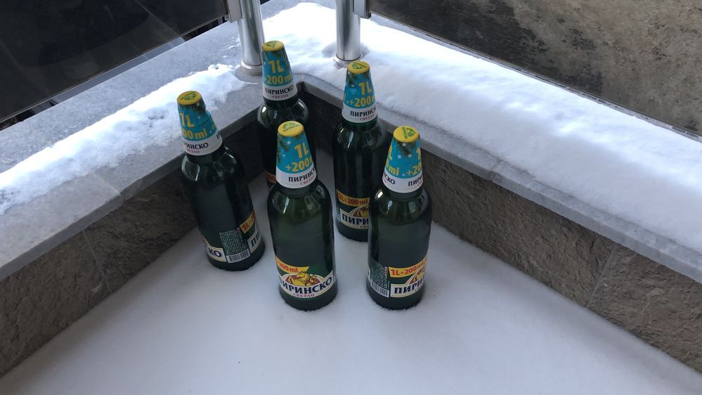 Legenda: Uma foto em close-up de cinco garrafas de cerveja deixadas para esfriar em uma varanda coberta de neve. (Local Guidel @FelipePK)