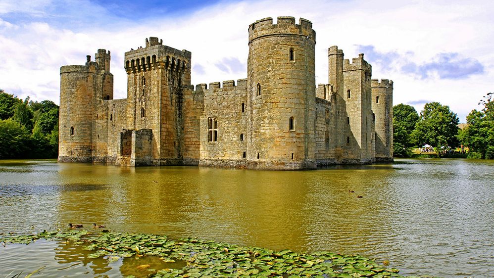 Caption: A photo of Bodium Castle in Robertsbridge, UK, taken on a partly cloudy day and surrounded by a moat. (Local Guide Van Quoc Hoang)