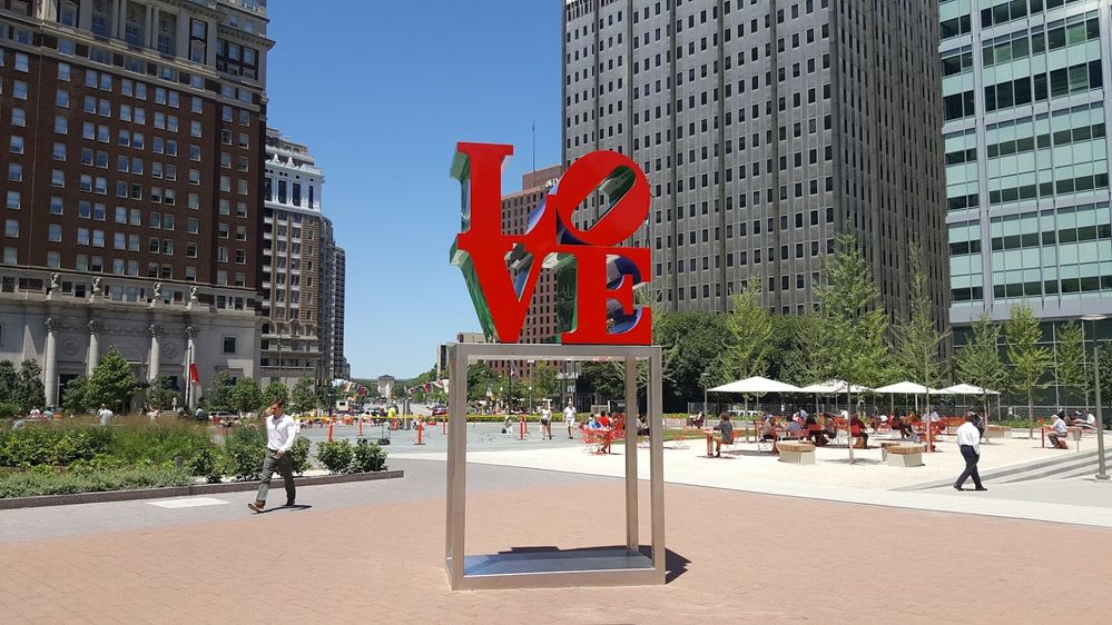 Caption: A photo of the Robert Indiana's iconic "LOVE" statue, a large red statue of the letters L and O stacked on top of a V and E on a silver metal base, in Love Park in Philadelphia. (Local Guide chandra shekar)