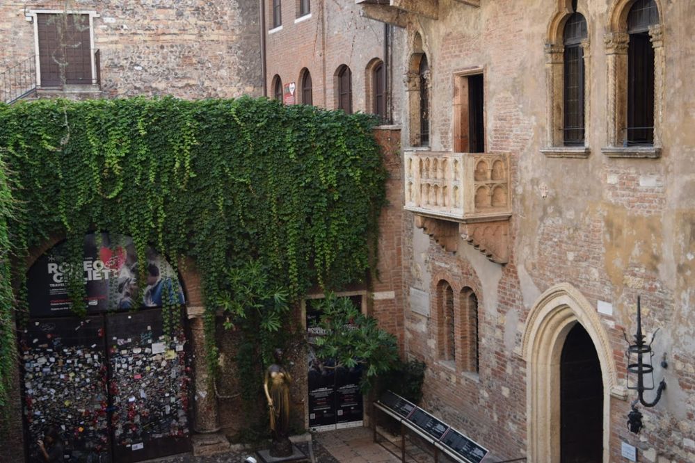 Caption: A photo of the brick and stone building known as Juliet’s House in Verona, Italy, showing the balcony some say inspired Shakespeare's “Romeo and Juliet” as well as the bronze Juliet statue in the courtyard below. (Local Guide Amanda)