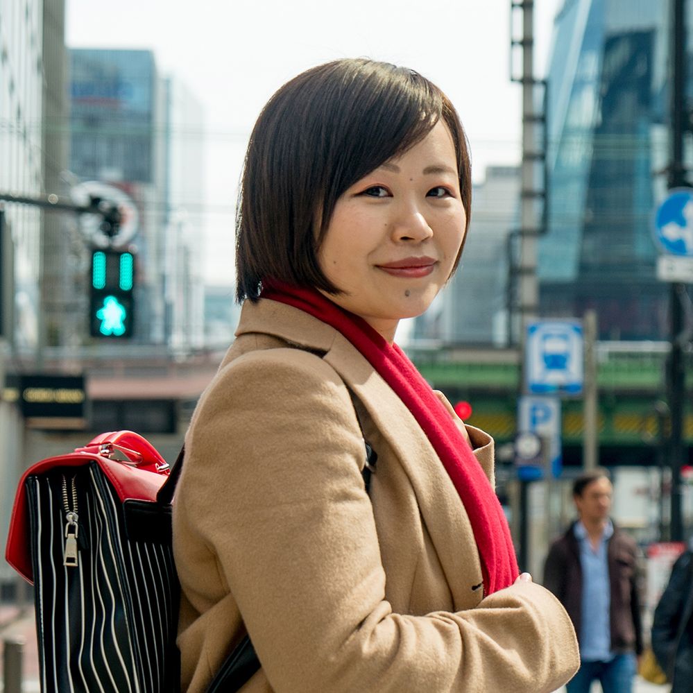 Caption: A photo of Local Guide Qianyun Fang wearing a backpack on a city street and smiling at the camera. (Ciel Lui)