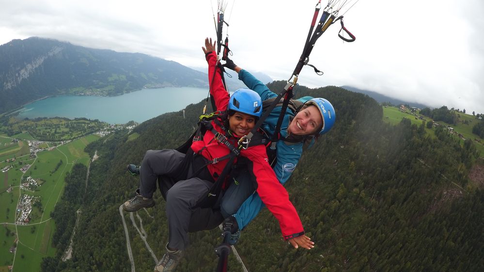 Caption: A photo of Local Guide Vandana hooked up to a parachute while skydiving with a woman skydiving instructor in Interlaken, Switzerland. (Courtesy of Vandana Bellur)