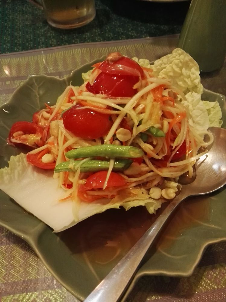 Caption: A photo of papaya salad on an iceberg leaf, made with shredded papaya and carrots, green beans, spicy chili, tomatoes, and peanuts, served on a leaf-shaped plate.  (Local Guide Inoue So)