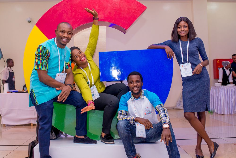 Caption: A photo of Local Guides posing in front of a statue of the Google logo at the Connect Live Abuja event at the Barcelona Hotel in Abuja, Nigeria.