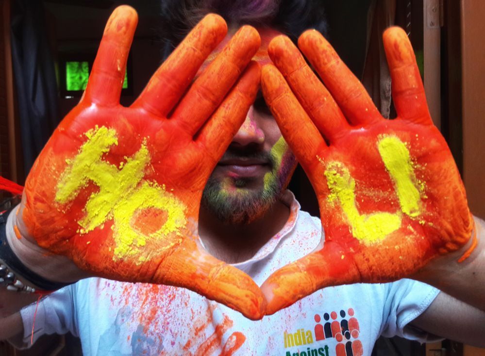 Caption: A photo of Local Guide @IshantHP_ig’s hands covered in saffron paint with the words “HOLI” written with yellow paint. (Local Guide @IshantHP_ig)