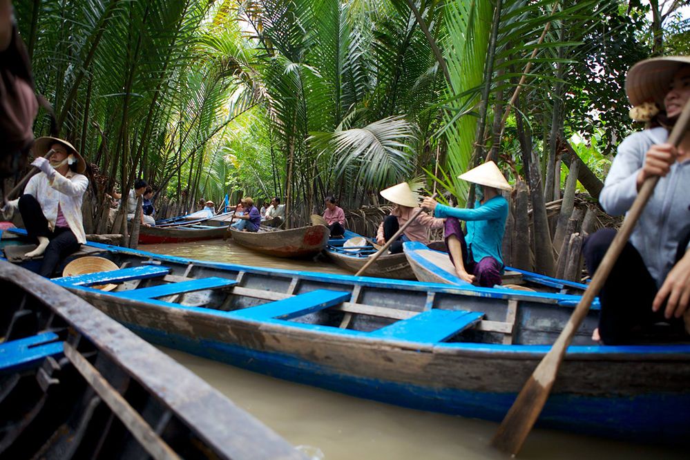 Caption: A photo of people with Asian conical hats rowing boats on the Mekong Delta in Mỹ Tho, Vietnam. (Local Guide Meng He)